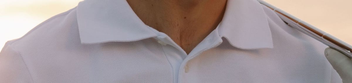 White piqué polo shirt showing the collar, buttoned placket and shoulder seam